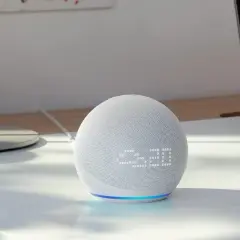 Echo Dot mit integriertem Temperatursensor zeigt 23:20 an. Ein Laptop mit Diagrammen steht daneben.