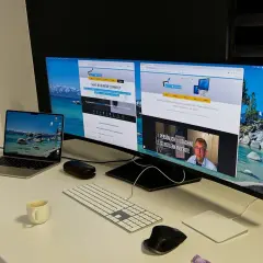Ein Arbeitsplatz mit mehreren Bildschirmen eingerichtet. Ein Laptop, eine Tastatur, Mäuse und eine Kaffeetasse stehen auf dem Schreibtisch.