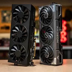 Zwei Grafikkarten, eine schwarze mit drei Lüftern und eine silberne mit "RADEON" Schriftzug, die an eine Radeon RX 9070 XT erinnert.