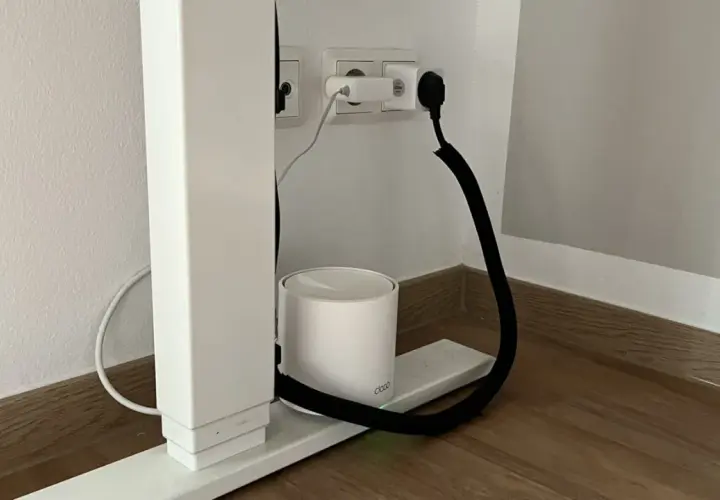 Ein weißer Router steht auf einem Sockel, während ein schwarzer Kabelkanal hilft, das Kabel unsichtbar zu verlegen.