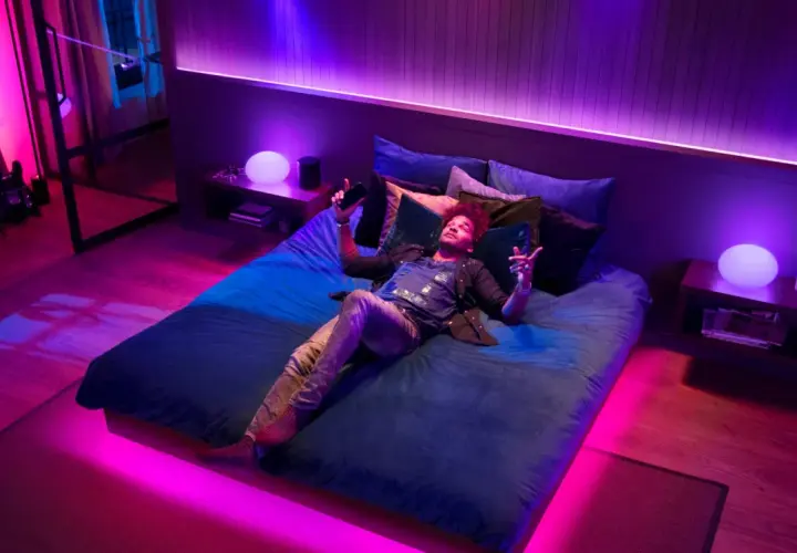 Mann liegt im Bett, umgeben von Philips Hue Lichtern, die sich im Takt von Spotify-Musik synchronisieren.