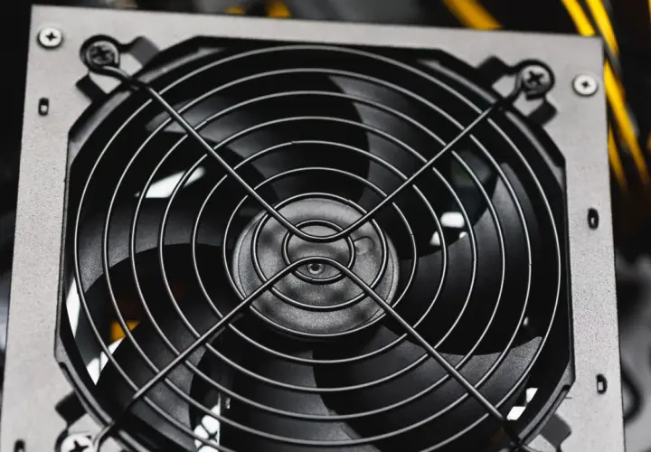 Nahaufnahme eines Lüfters eines PC-Netzteils, bereit für den psu test. Gelbe Kabel im Hintergrund.
