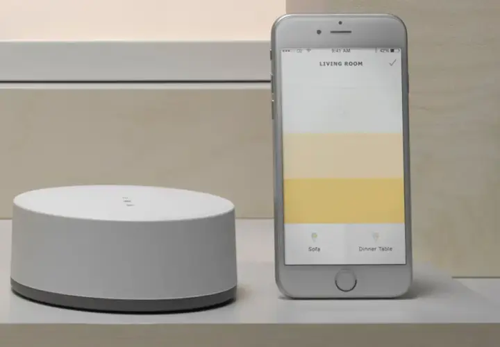 Ein Smartphone zeigt eine App zur Steuerung von adaptiven Licht. Daneben ein weißer Hub.
