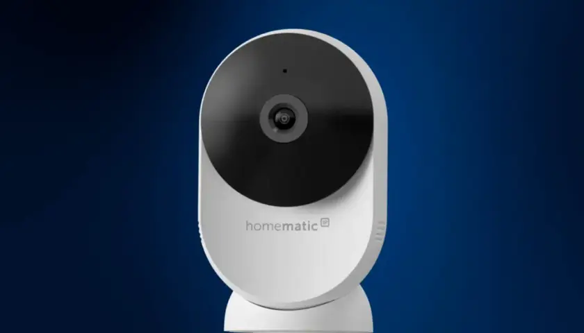 Weiße Homematic IP Überwachungskamera mit schwarzem Objektiv vor blauem Hintergrund.