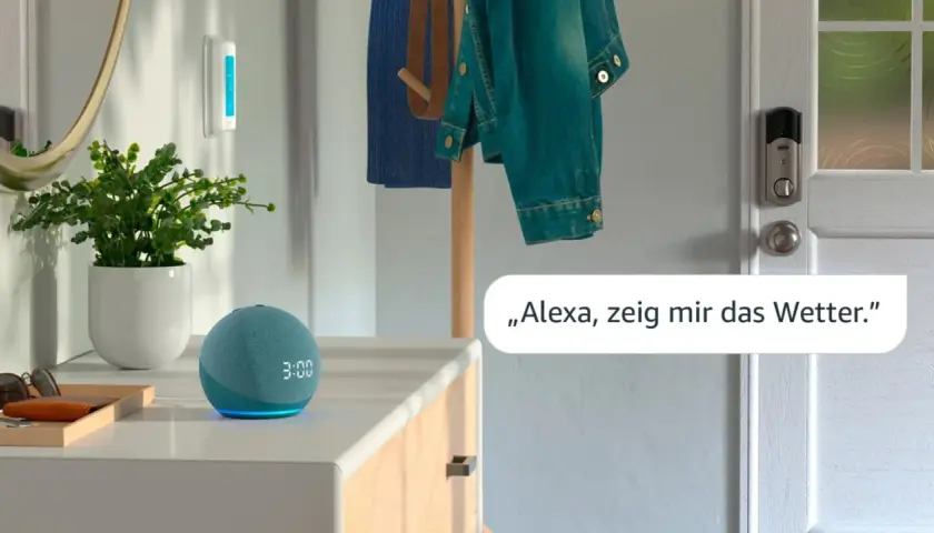 Ein blauer Echo Dot mit leuchtender Anzeige steht neben einer Pflanze. Eine Stimme fragt: "Alexa, zeig mir das Wetter.