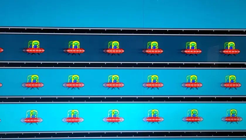 Mehrere rote UFOs mit grünen Aliens fliegen auf einem blauen Hintergrund. Deutliches **Monitor Ghosting** erzeugt Schlieren.
