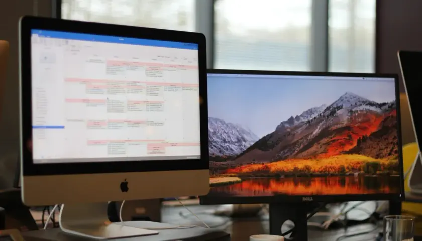 Zwei Monitore getrennt nutzen: Links ein Kalender, rechts eine Berglandschaft mit See. Effizientes Arbeiten und entspannender Ausblick.