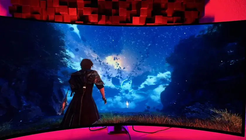 Breiter 21:9-Monitor zeigt eine Fantasy-Landschaft mit schwebenden Felsen und Sternenhimmel. Eine Figur blickt in die Ferne.