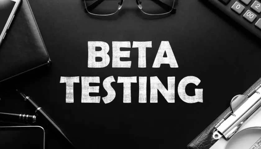 BETA TESTING: Ein Smartphone, Brille und ein Taschenrechner liegen neben der Aufschrift. Die offene Beta-Phase beginnt.