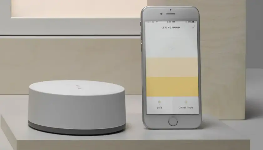Ein Smartphone zeigt eine App zur Steuerung von adaptiven Licht. Daneben ein weißer Hub.