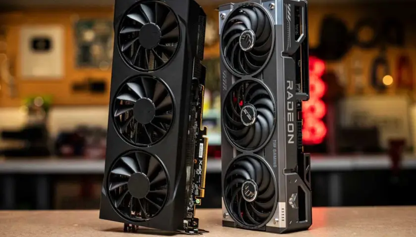 Zwei Grafikkarten, eine schwarze mit drei Lüftern und eine silberne mit "RADEON" Schriftzug, die an eine Radeon RX 9070 XT erinnert.