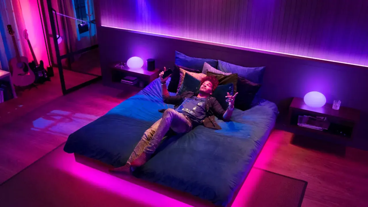 Mann liegt im Bett, umgeben von Philips Hue Lichtern, die sich im Takt von Spotify-Musik synchronisieren.