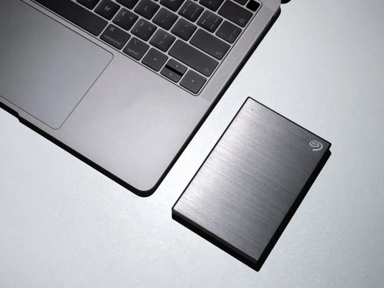 Silbernes Laptop neben einer externen Seagate Hybrid HDD.