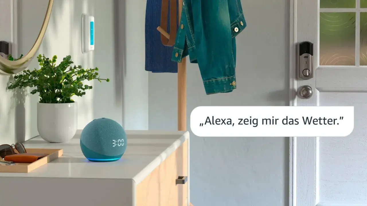 Ein blauer Echo Dot mit leuchtender Anzeige steht neben einer Pflanze. Eine Stimme fragt: "Alexa, zeig mir das Wetter.