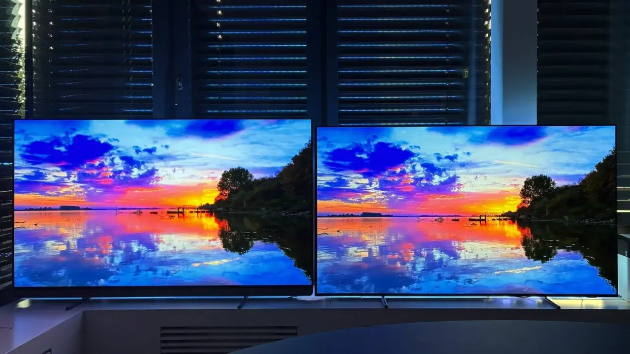 Zwei LG Ambilight Fernseher zeigen einen dramatischen Sonnenuntergang über dem Wasser. Die Lichter spiegeln sich im ruhigen See.