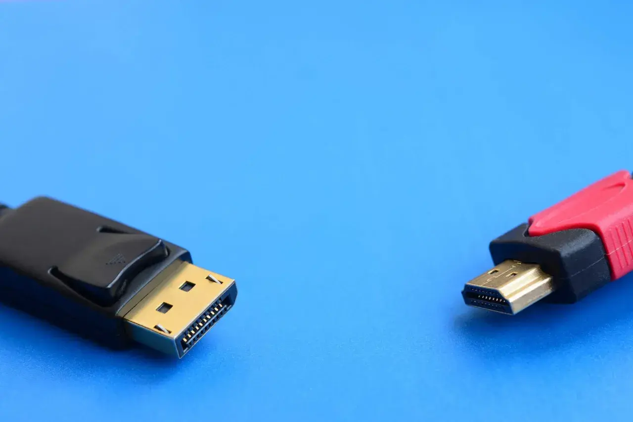 Ein DisplayPort-Stecker und ein HDMI-Stecker liegen nebeneinander. Verschiedene DisplayPort-Versionen bieten unterschiedliche Übertragungsraten.