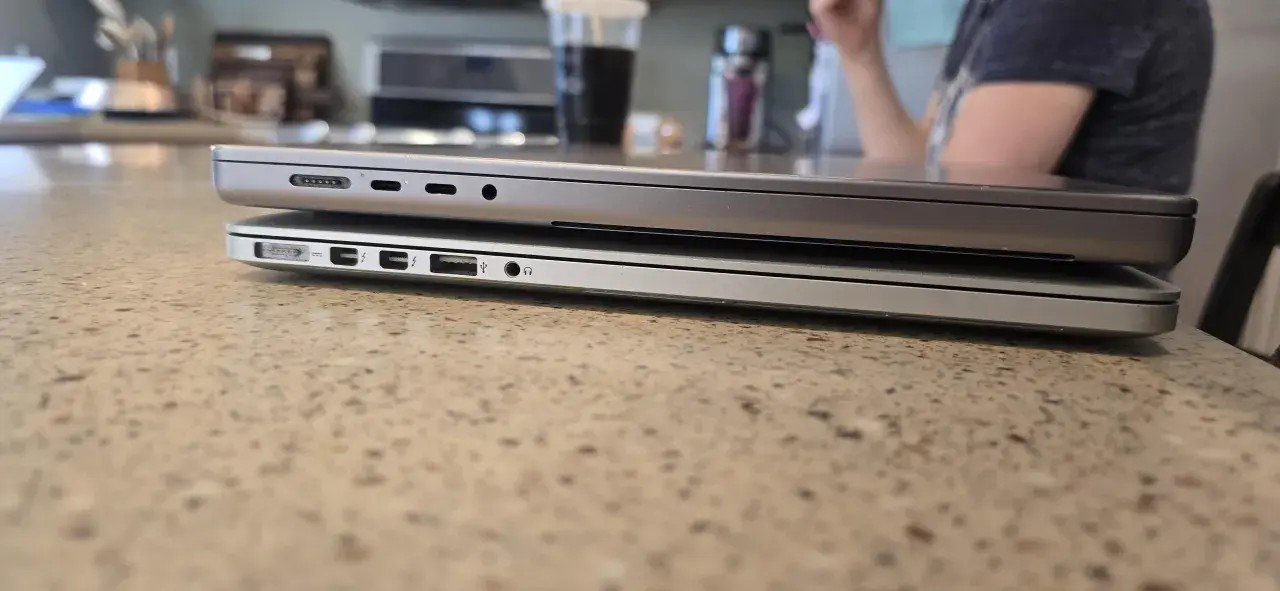Zwei MacBooks liegen übereinander. Das untere Modell hat mehr Anschlüsse. Das geringe MacBook Air Gewicht macht es zum idealen Reisebegleiter.