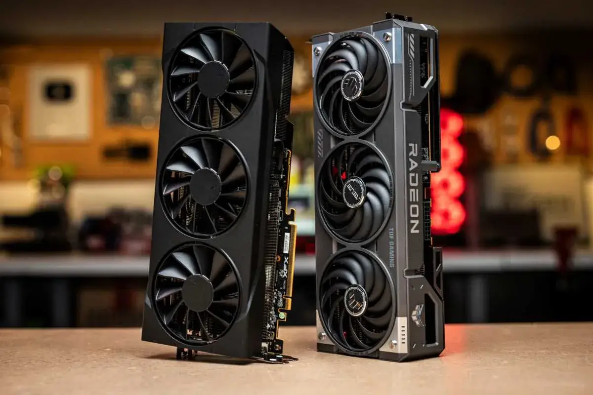 Zwei Grafikkarten, eine schwarze mit drei Lüftern und eine silberne mit "RADEON" Schriftzug, die an eine Radeon RX 9070 XT erinnert.