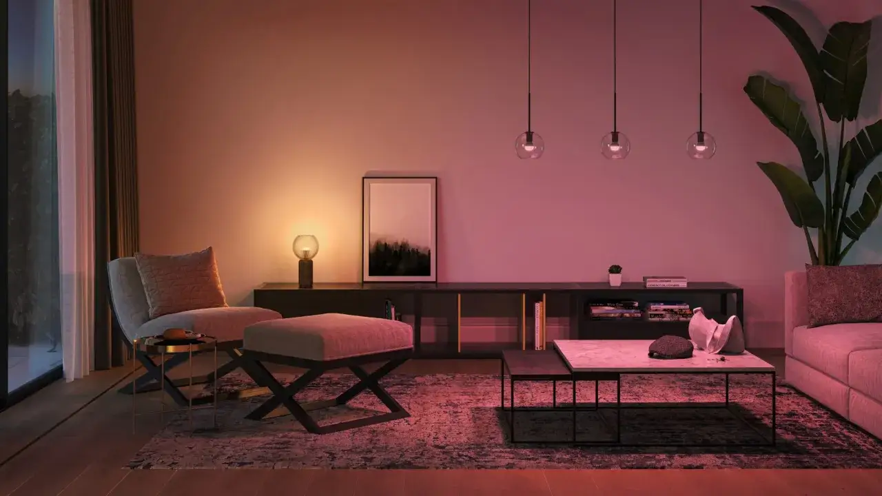 Gem&uuml;tliches Wohnzimmer mit Philips Hue Ideen: Sessel, Beistelltisch, Teppich, Couchtisch, Sideboard mit Deko und Bilder. Stimmungsvolle Beleuchtung in warmen T&ouml;nen.
