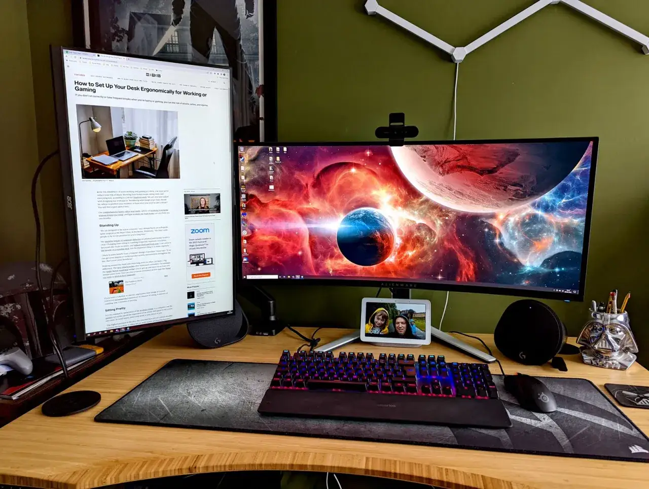 Ein Schreibtisch im 21:9-Format mit zwei Monitoren, einer davon vertikal, und einer Tastatur mit RGB-Beleuchtung. Der Hauptmonitor zeigt ein Weltraum-Wallpaper.