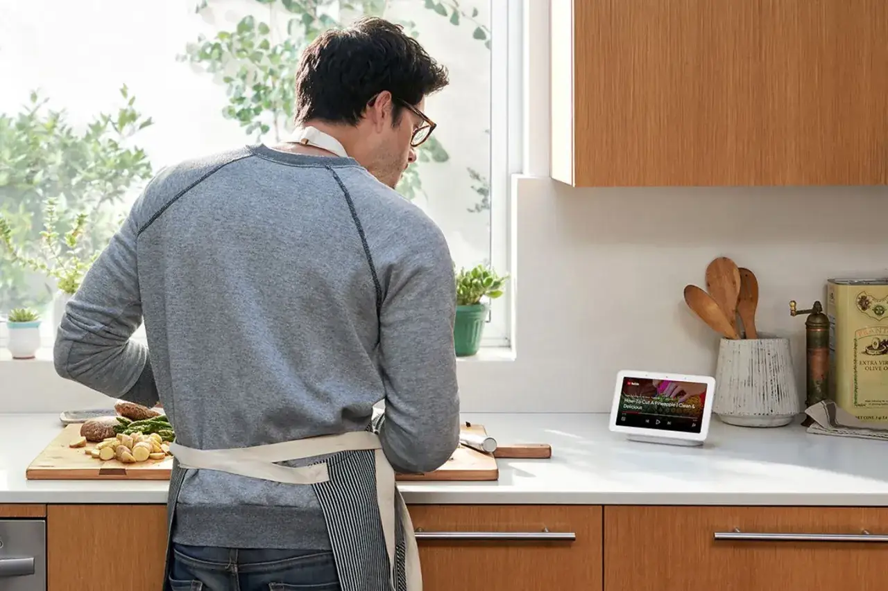Mann kocht mit Hilfe des Google Nest Hub 3, der ein Rezept anzeigt.
