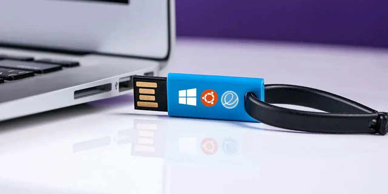 USB-Stick mit Windows-, Ubuntu- und Elementary OS-Logos, bereit f&uuml;r die Installation auf einem Laptop.