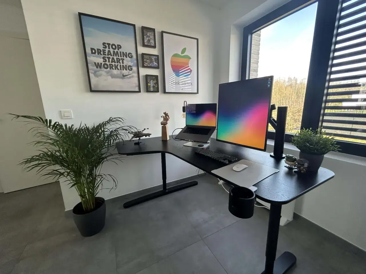 Schreibtisch mit LG DualUp Monitor, Laptop, Tastatur und Maus. Dekoriert mit Postern und Pflanzen.