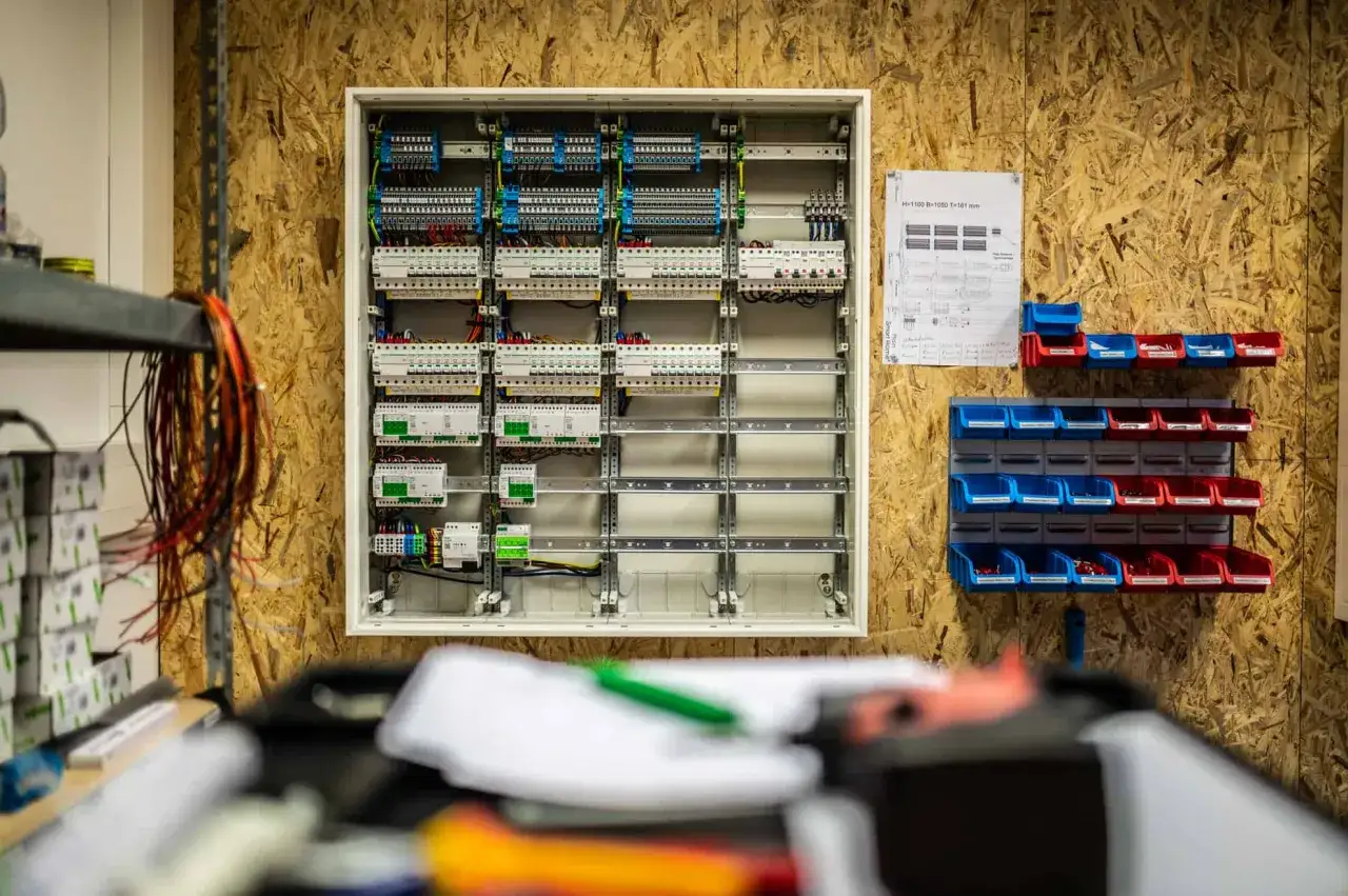 Detailaufnahme eines Schaltschranks, der f&uuml;r die Smart Home Planung vorbereitet wird. Daneben h&auml;ngen Kabel und eine Werkzeugwand mit Kleinteilen.